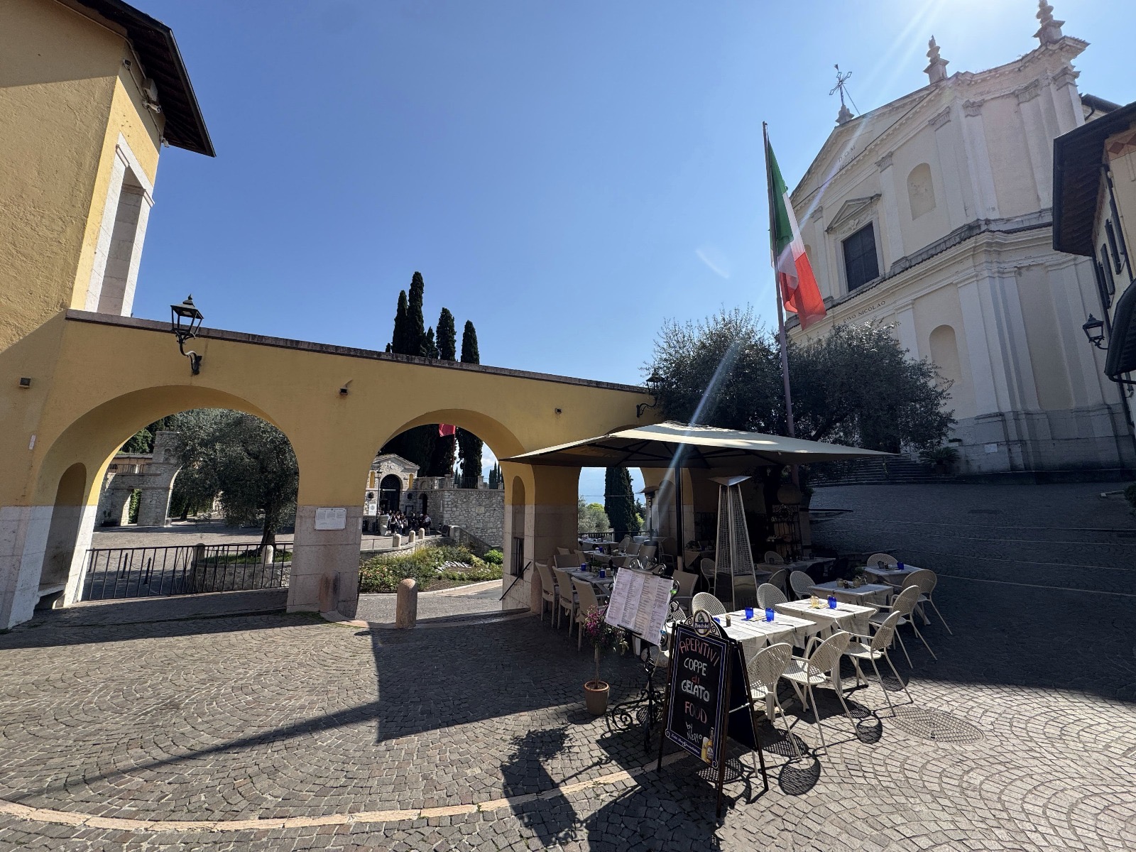 Tavoli apparecchiati sotto gli archi in Piazza dei Caduti, con la chiesa sullo sfondo